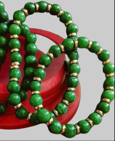 House of Joy green beaded bracelets with 18k gold plated accents on a red wooden box against a green background